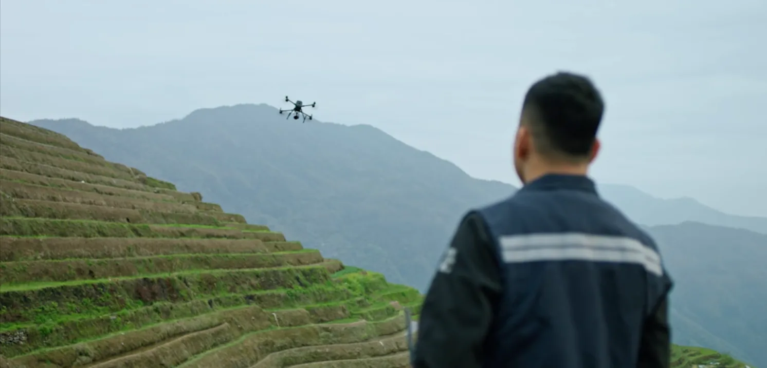 Surveyor watching an RTK drone fly over terraced Costa Rican hillsides during a field survey